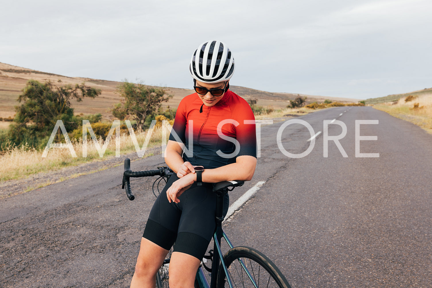 Woman cyclist in sportswear leaning on her bicycle checking smartwatch 