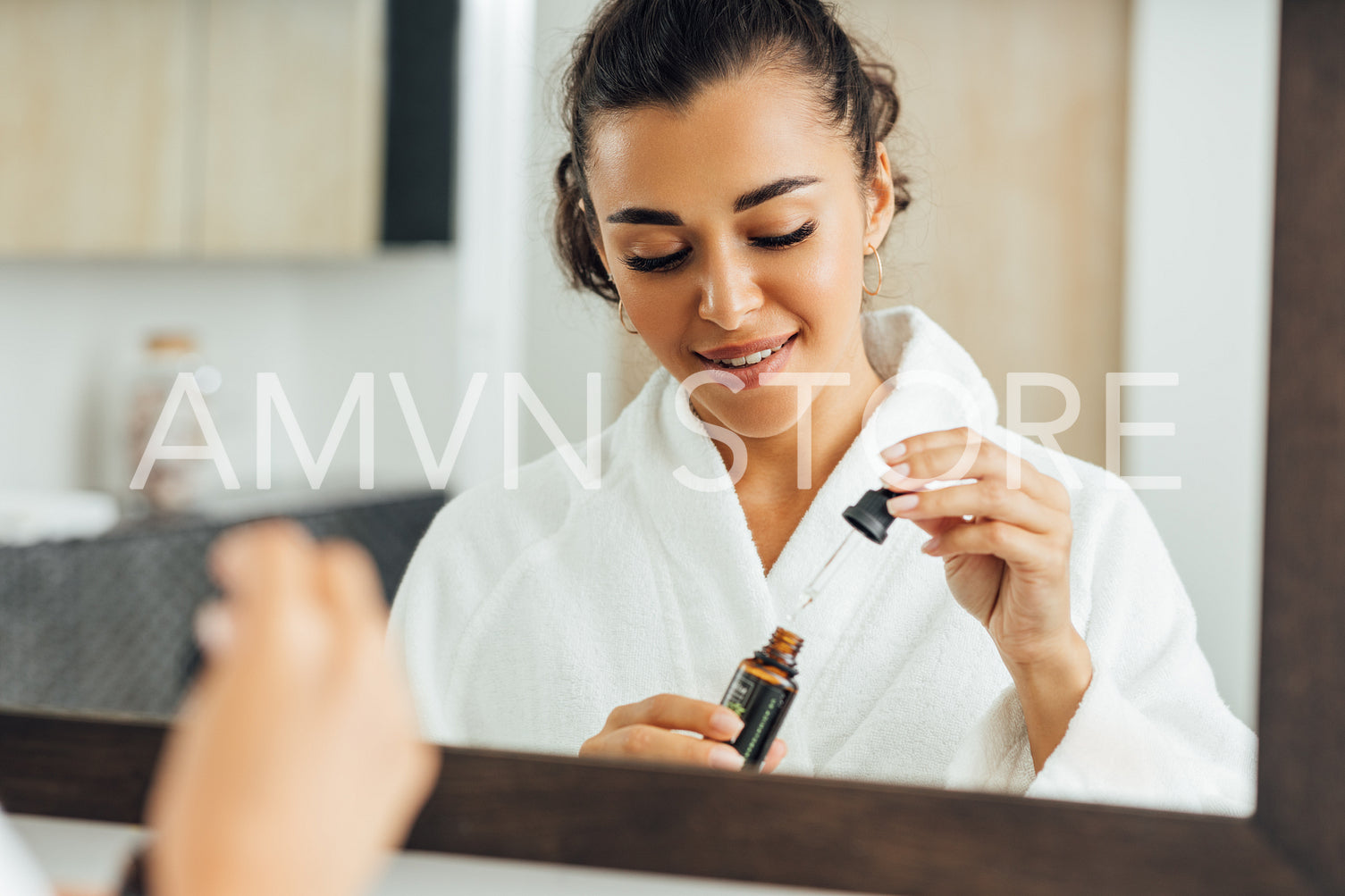 Young woman in bathrobe holding a skin oil. Smiling female preparing to apply hyaluronic acid on face.	