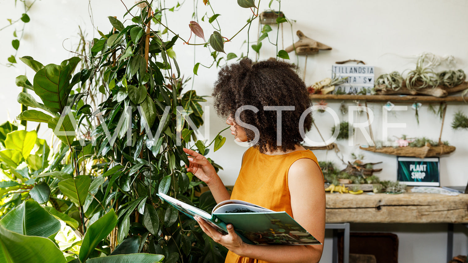 Young woman holding a book and observe a plant in workshop	