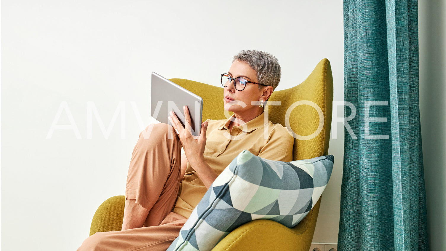 Stylish senior woman holding a digital tablet while sitting in living room	