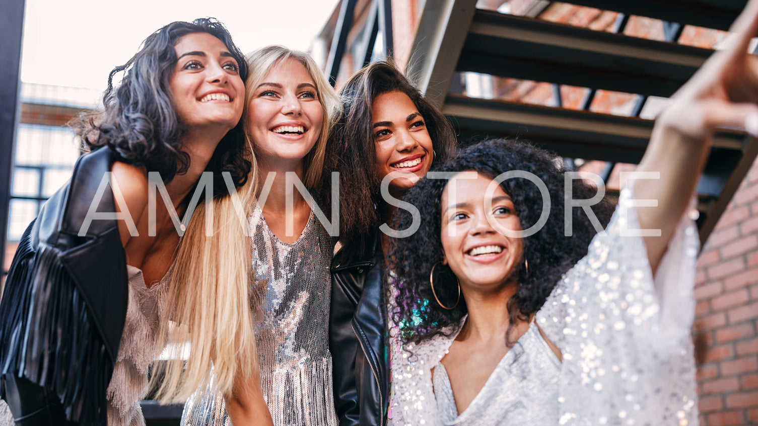 Four women on the street look at one point and smiling	