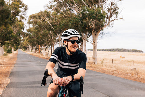 Smiling woman cyclist relaxing during ride on empty country road