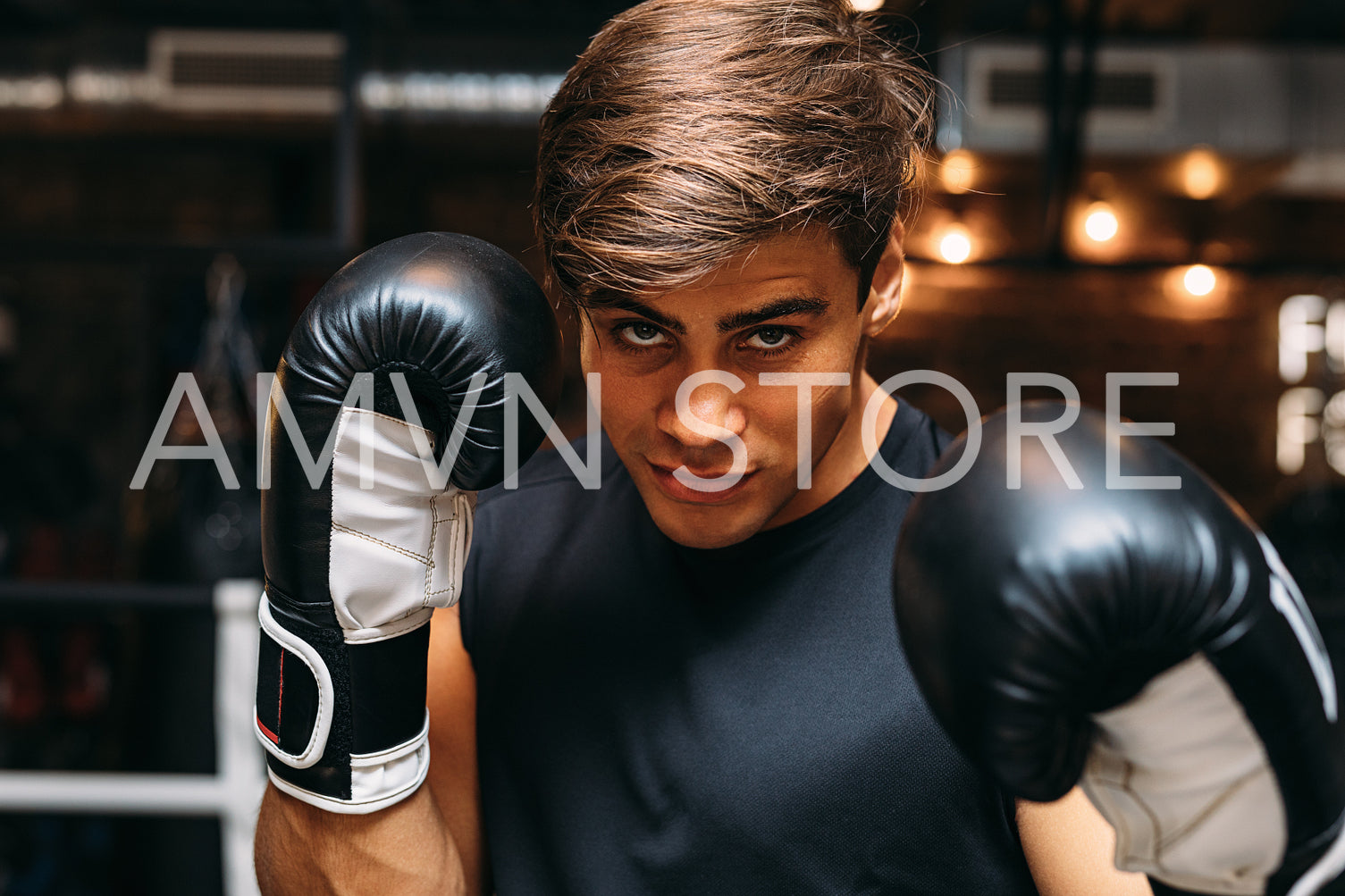 Man boxer in ring wearing boxing gloves, looking at camera	