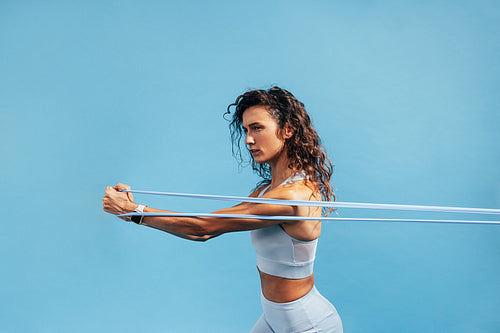 Strong woman workout with resistance band. Side view of young female using stretch bands.