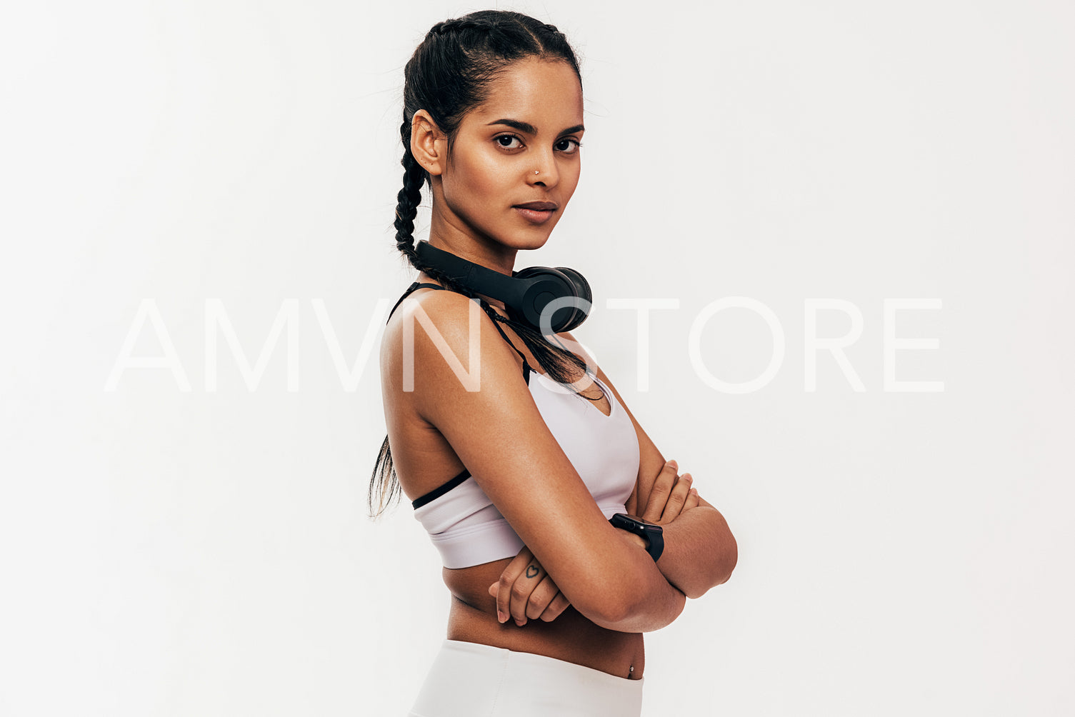 Confident woman in sportswear standing against white background with crossed arms