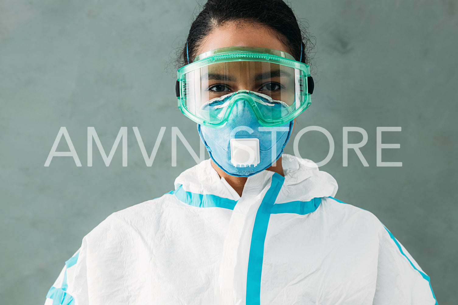 Female medical worker in a white protective suit, eyeglasses, and mask looking straight of a camera	