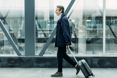 Side view of male tourist walking indoors with luggage