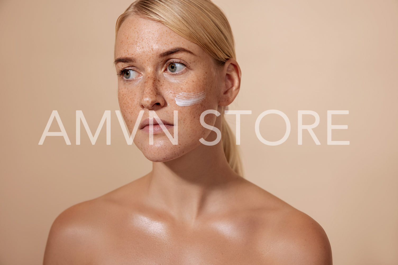 Studio portrait of a young woman with a cream on her face lookin