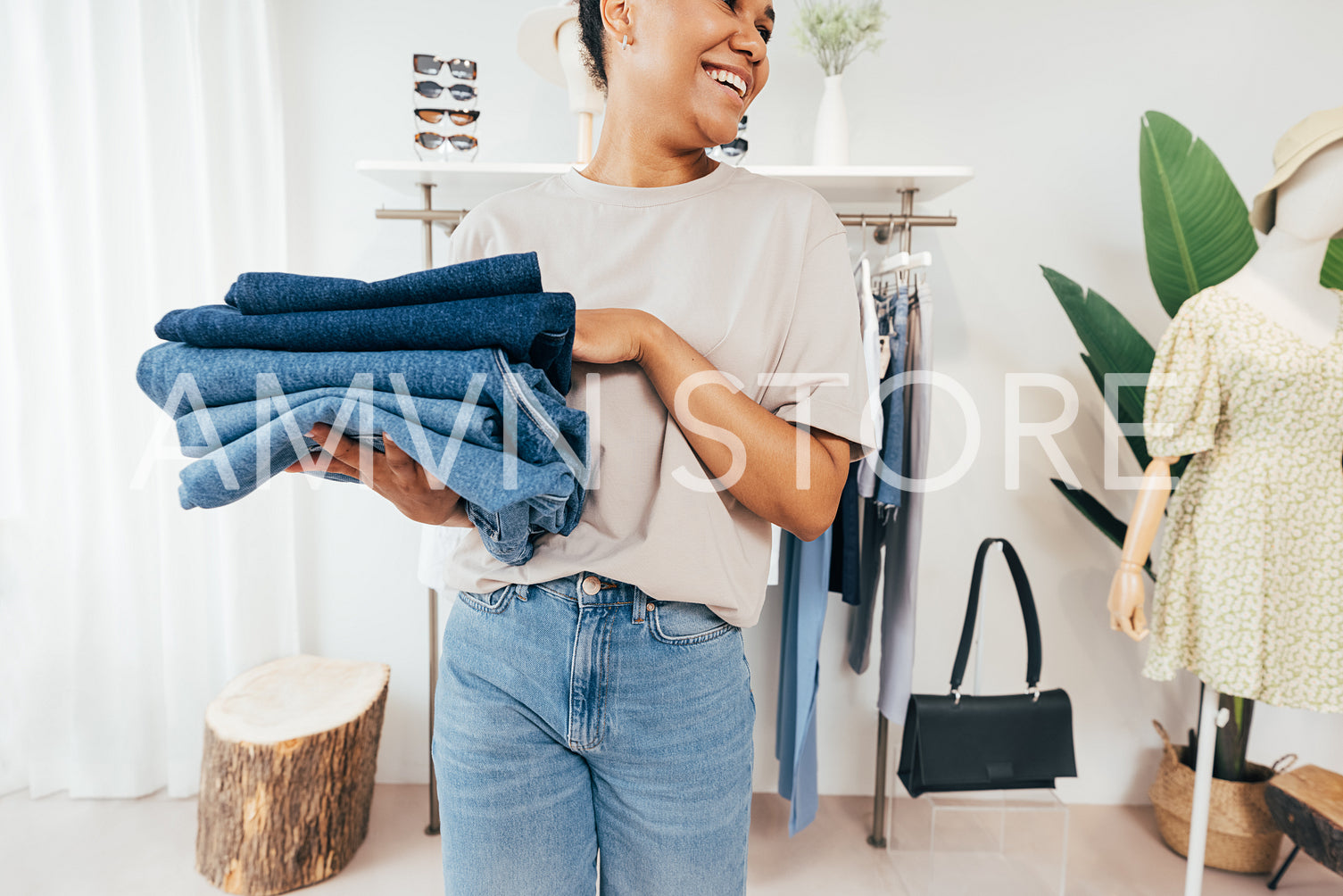 Cropped shot of a young saleswoman holding stack of folded clothes looking away