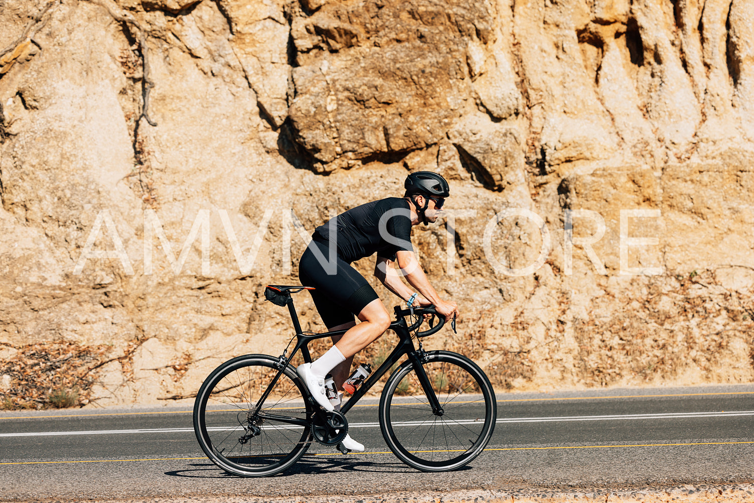 Side view of a young male cyclist riding his bicycle on a road while going up on a hill