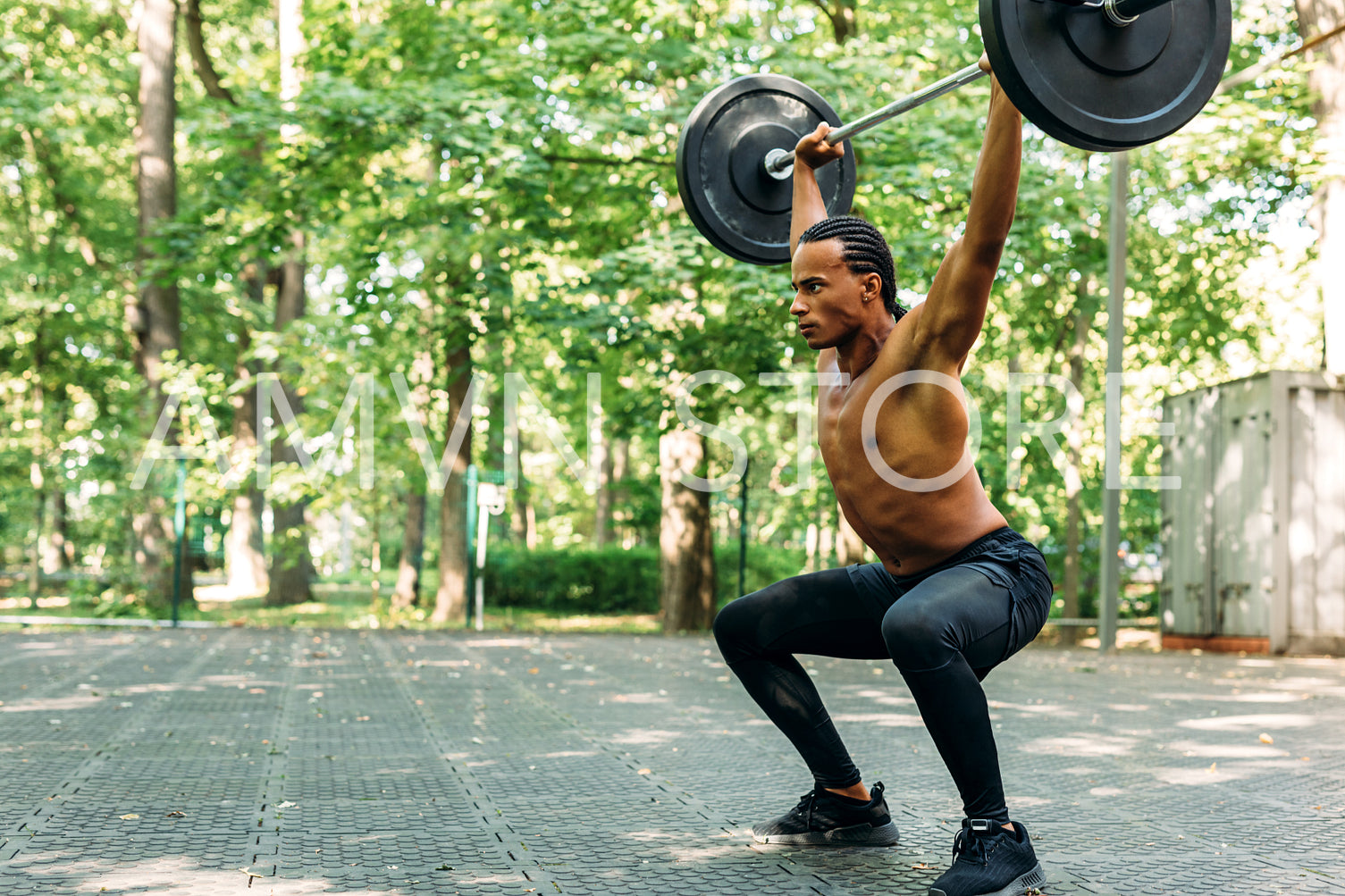 Young athlete performing deadlift exercise with weight bar outdoors	