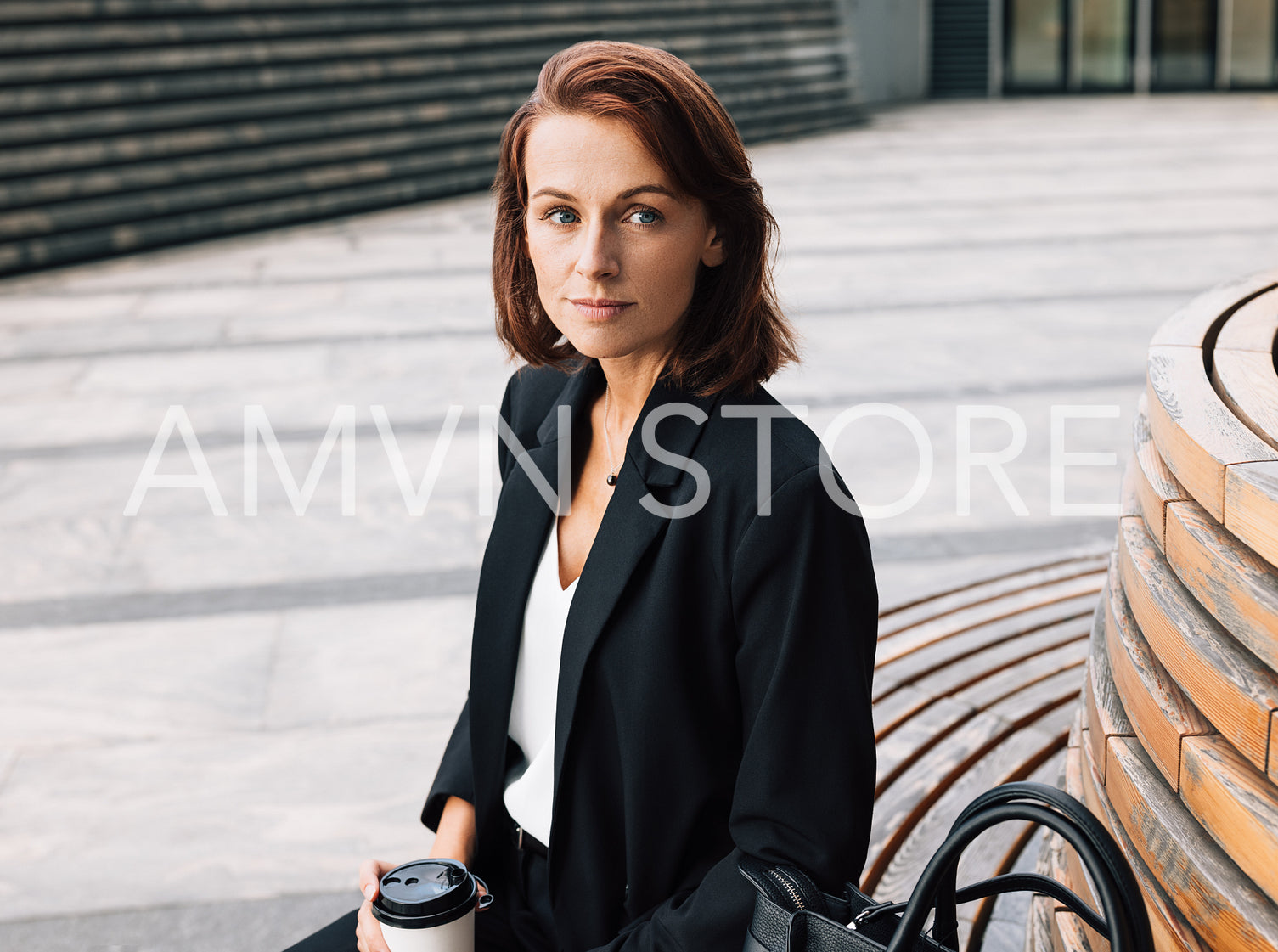 Middle-aged business woman sitting outdoors during lunch holding coffee