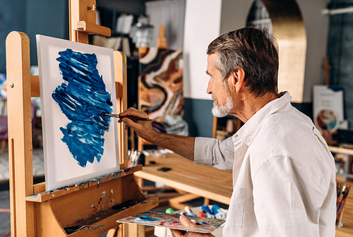 Enthusiastic artist working in his studio drawing on canvas