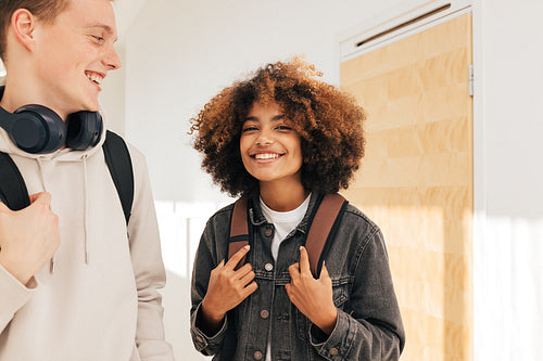 Two cheerful classmates standing together in corridor