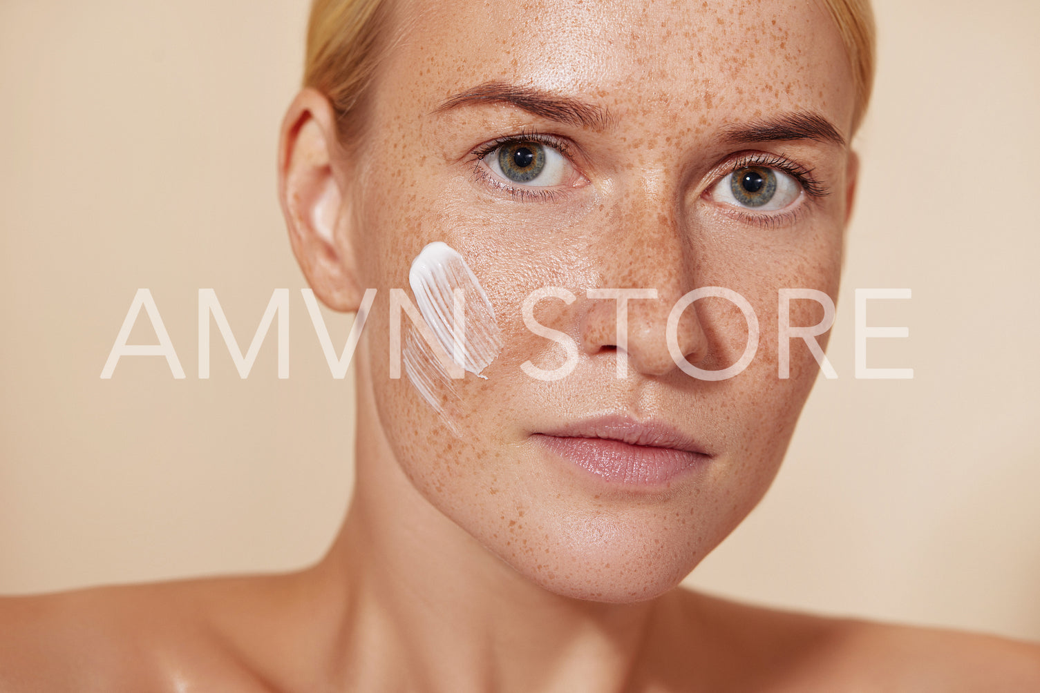 Close up portrait of a woman with perfect smooth skin. Female with freckled skin and cream on a cheek.