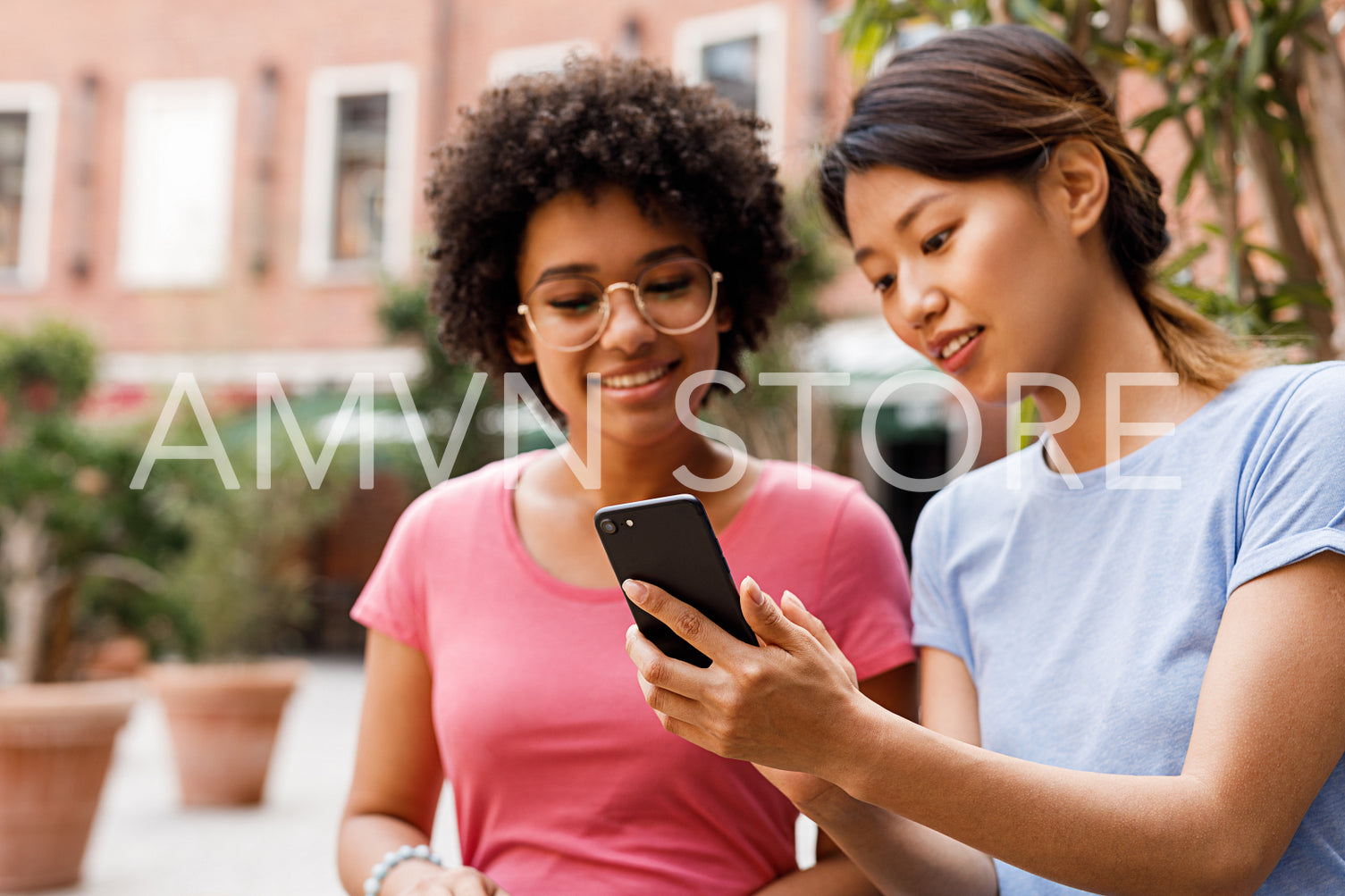 Two female friends looking at smartphone and talking	