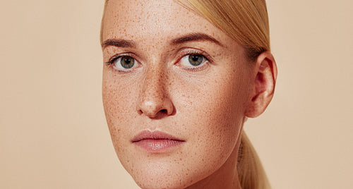 Cropped portrait of a young beautiful woman with freckles. Close-up of female with smooth skin.