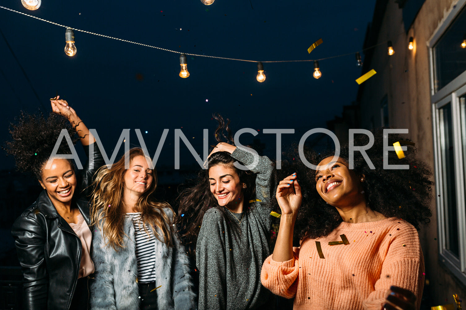 Four beautiful women dancing on a terrace at night	