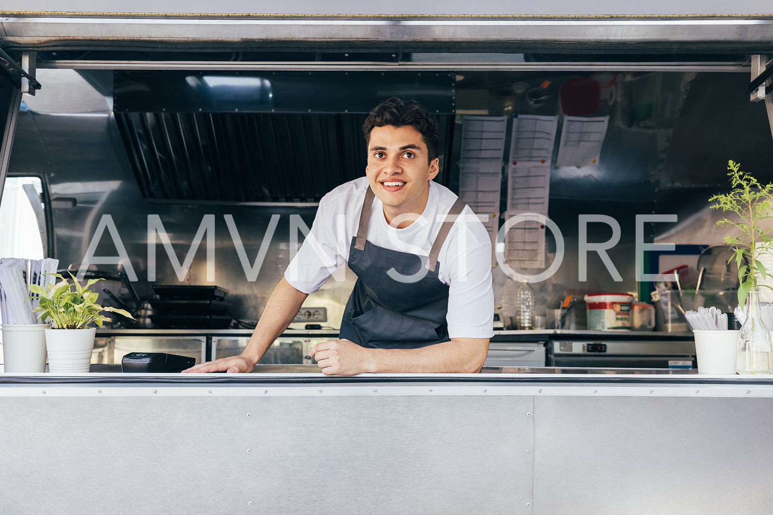 Portrait of a salesman in food truck leaning on counter and looking away