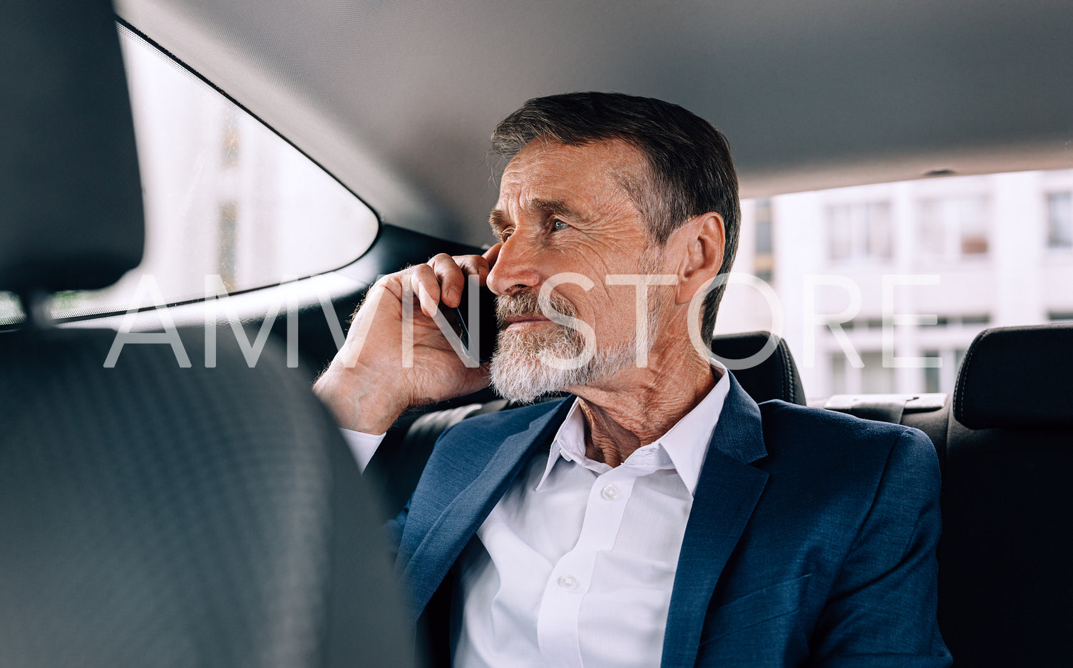 Pensive senior man holding a cell phone and looking on window while sitting in car	