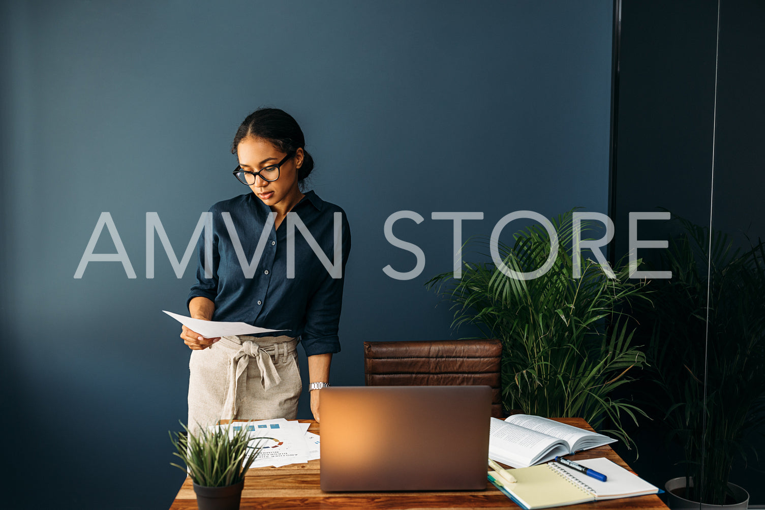 Young woman working from home standing at a desk and looking on documents	