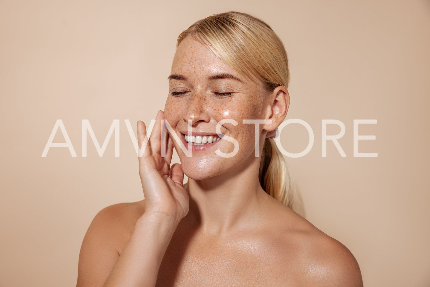 Happy woman with blond hair touching face in studio