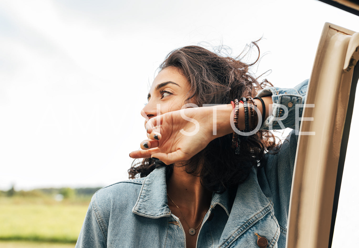 Young woman leaning on a car looking away during a summer trip