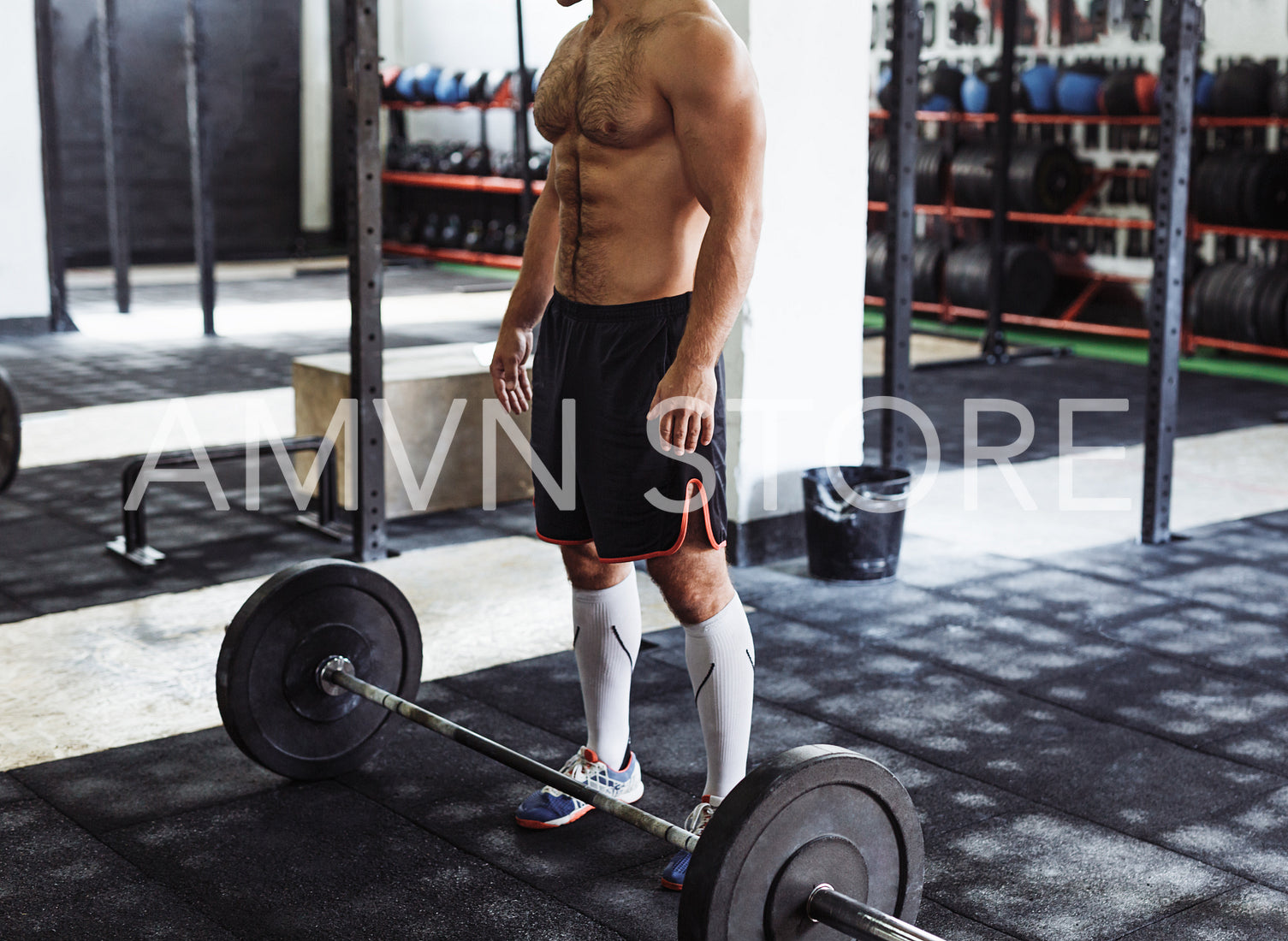 Unrecognizable man standing with heavy weights barbell on gym floor	