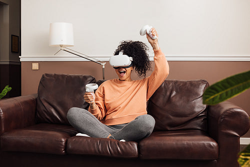 Excited female gamer using virtual reality headset while sitting