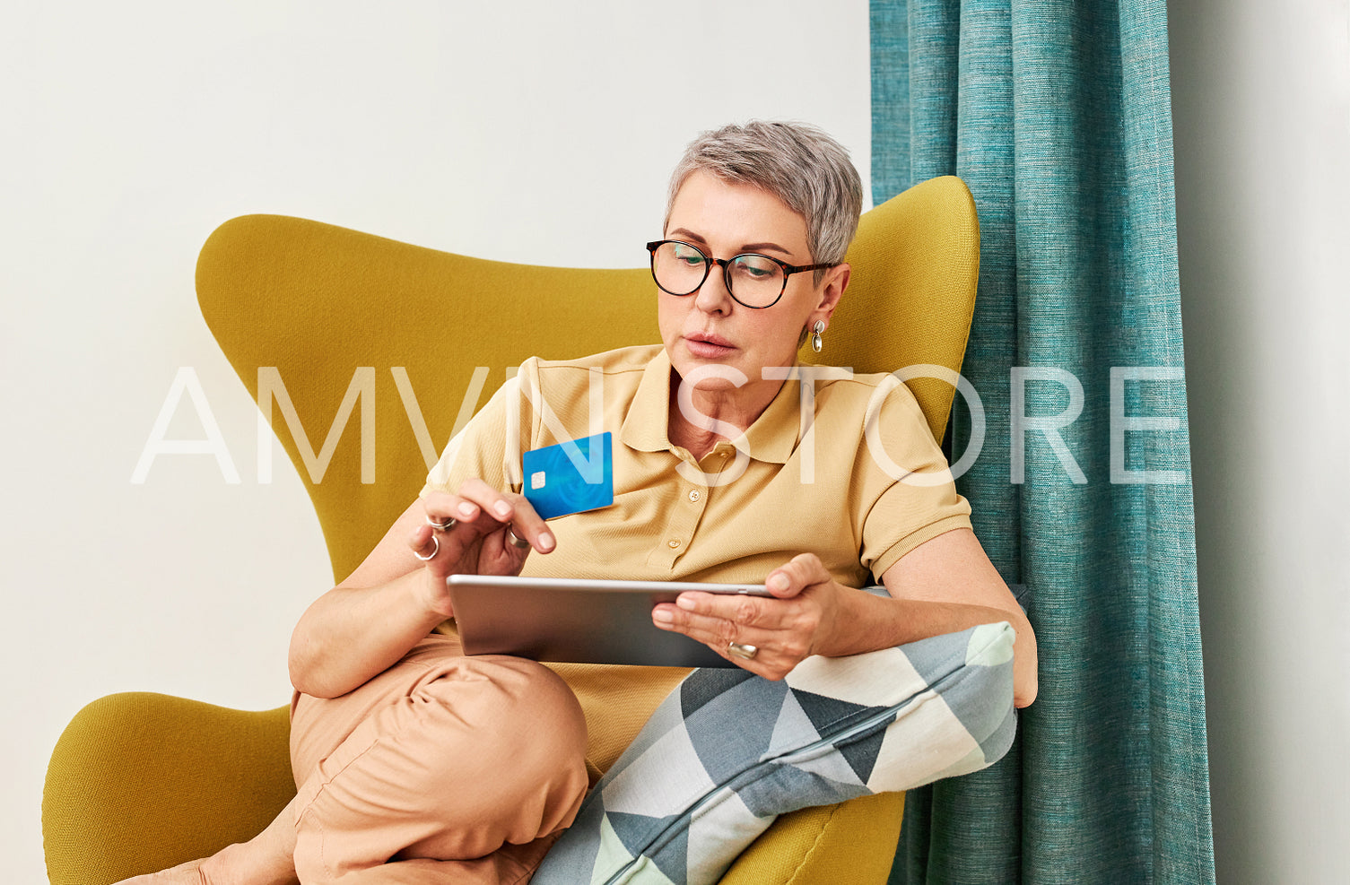 Mature woman in casuals paying by credit card while online shopping from home	