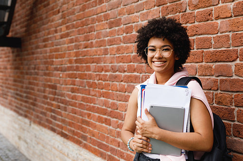 Young female student with books and digital tablet at campus