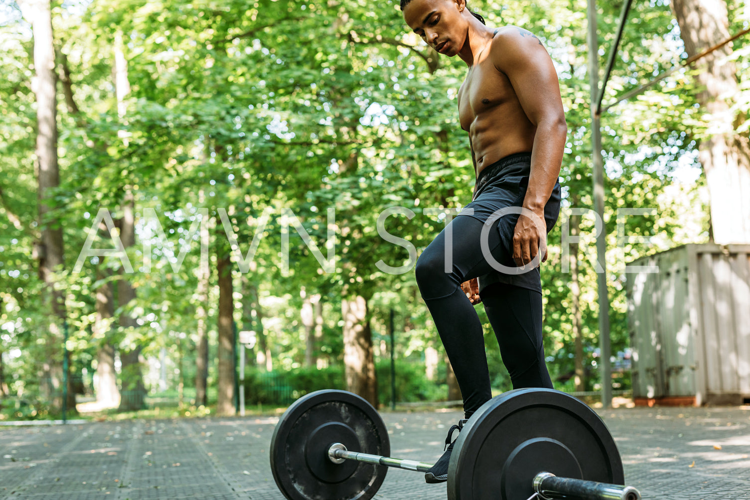 Side view of a young bare-chest athlete adjusting barbell for training	