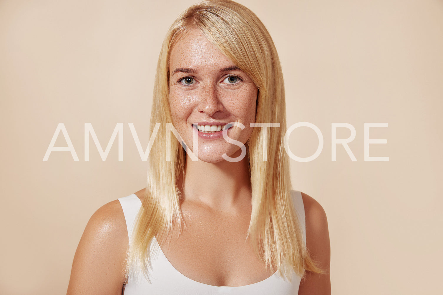 Portrait of a beautiful woman with freckles in studio. Young female with perfect skin against a beige backdrop.