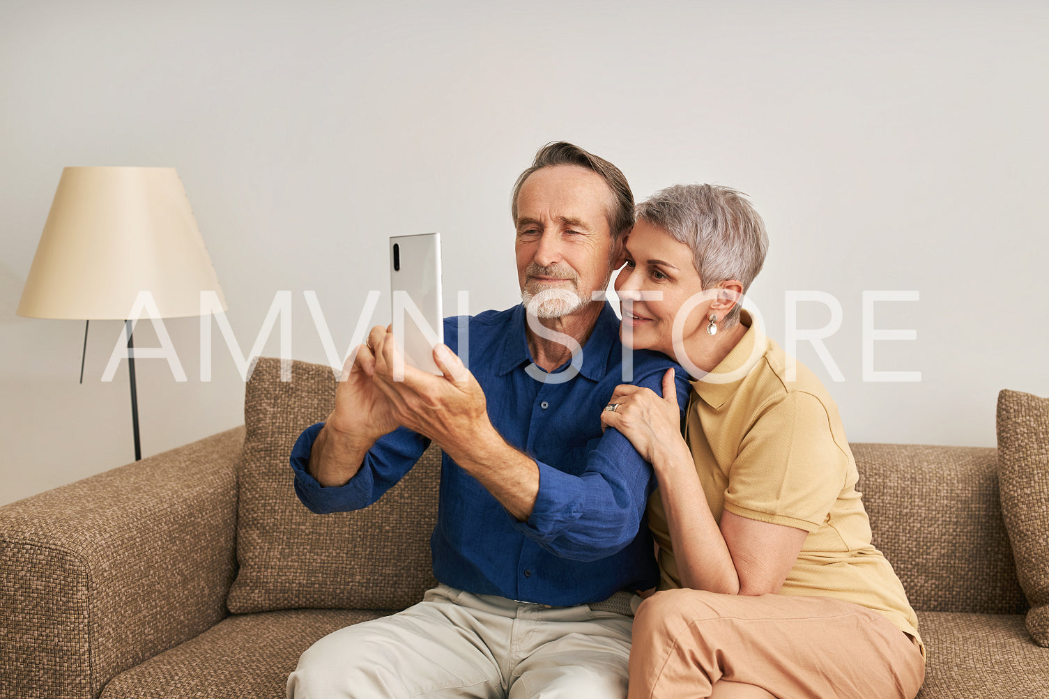 Senior couple spending time at home together. Elderly people taking a selfie while sitting on a couch.	