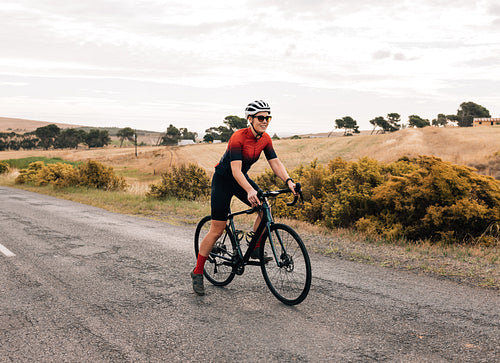 Professional woman cyclist starting to ride on empty countryside road