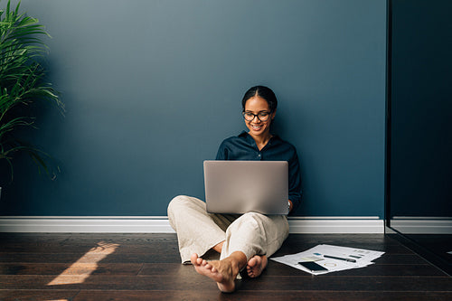 Freelancer sitting on the floor working on a laptop computer from home