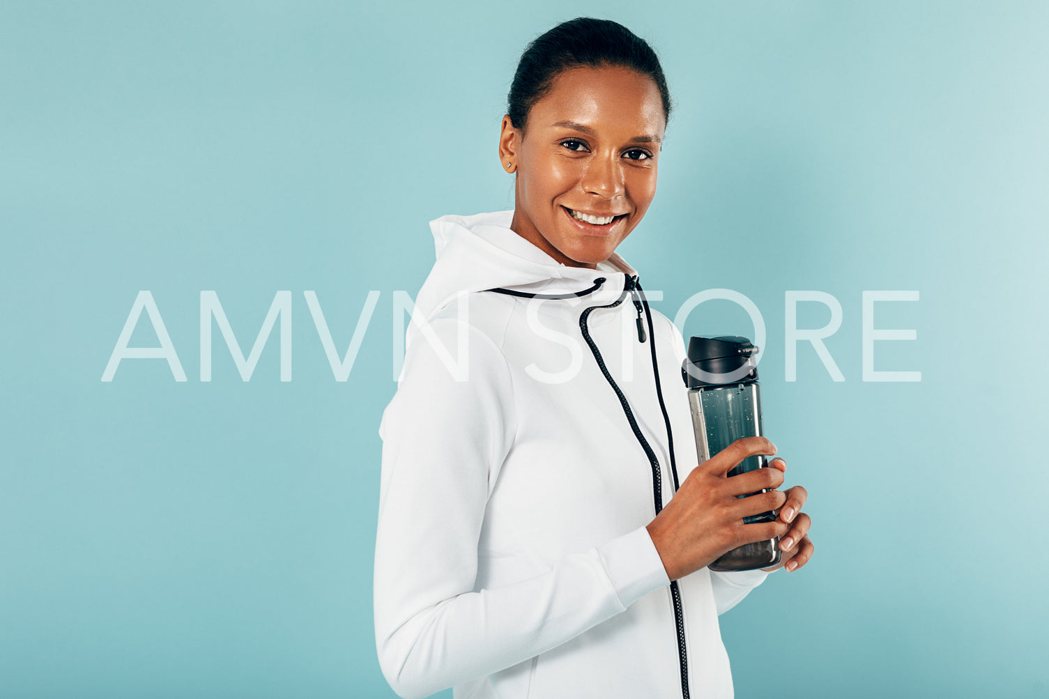 Happy young woman taking a break after exercising holding a water bottle	