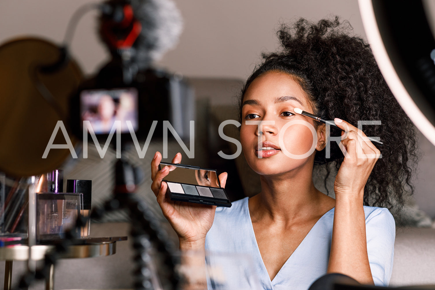 Female video blogger applying make up on face in living room	