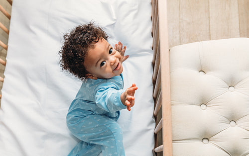 Portrait of a happy baby boy lying in his crib