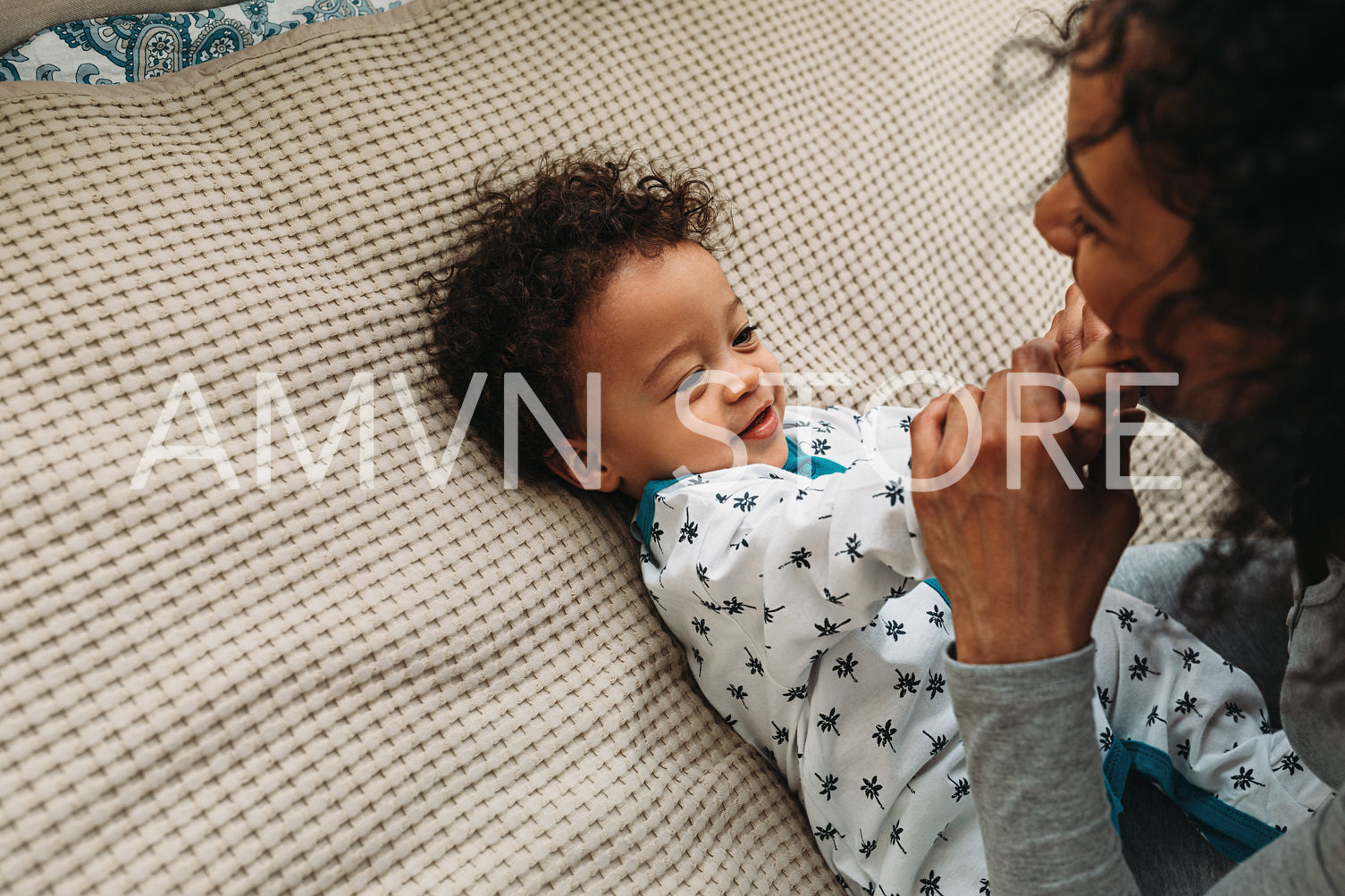 Cute baby boy playing with mother on a bed	