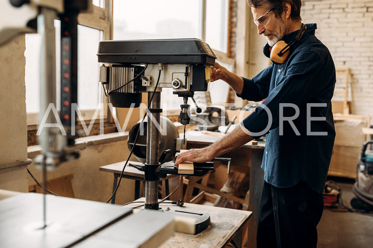 Carpenter drilling wood on machine. Male carpenter working in his workshop.	