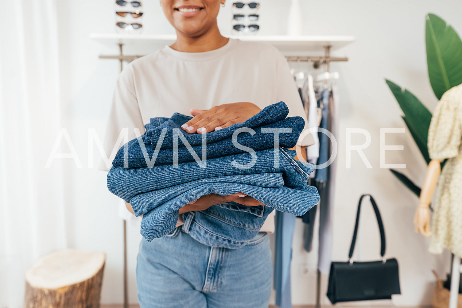 Close-up of saleswoman carrying clothing in a small retail store. Cropped shot of female holding a pile of jeans.