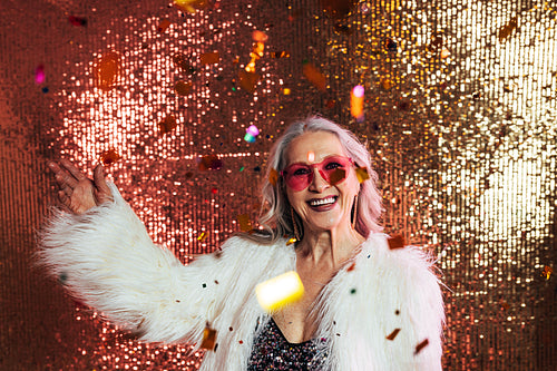 Happy senior woman in pink eyeglasses and white fur coat having