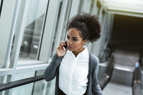 Woman making phone call while lifting up on escalator