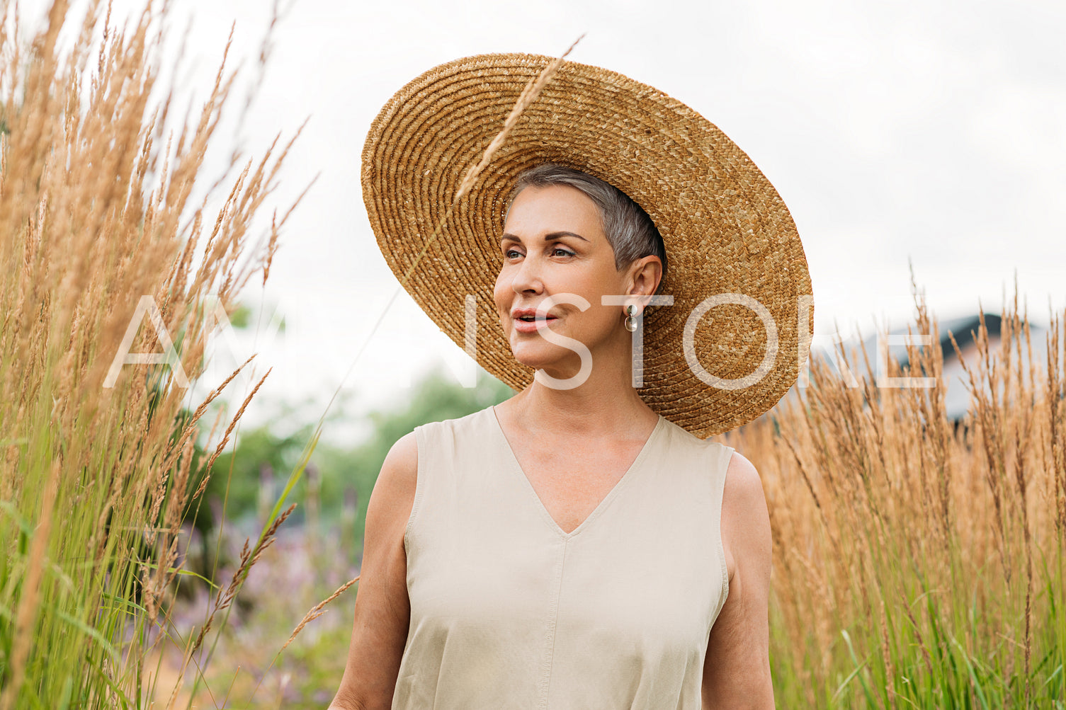 Woman in big straw hat looking away while standing on the field at day