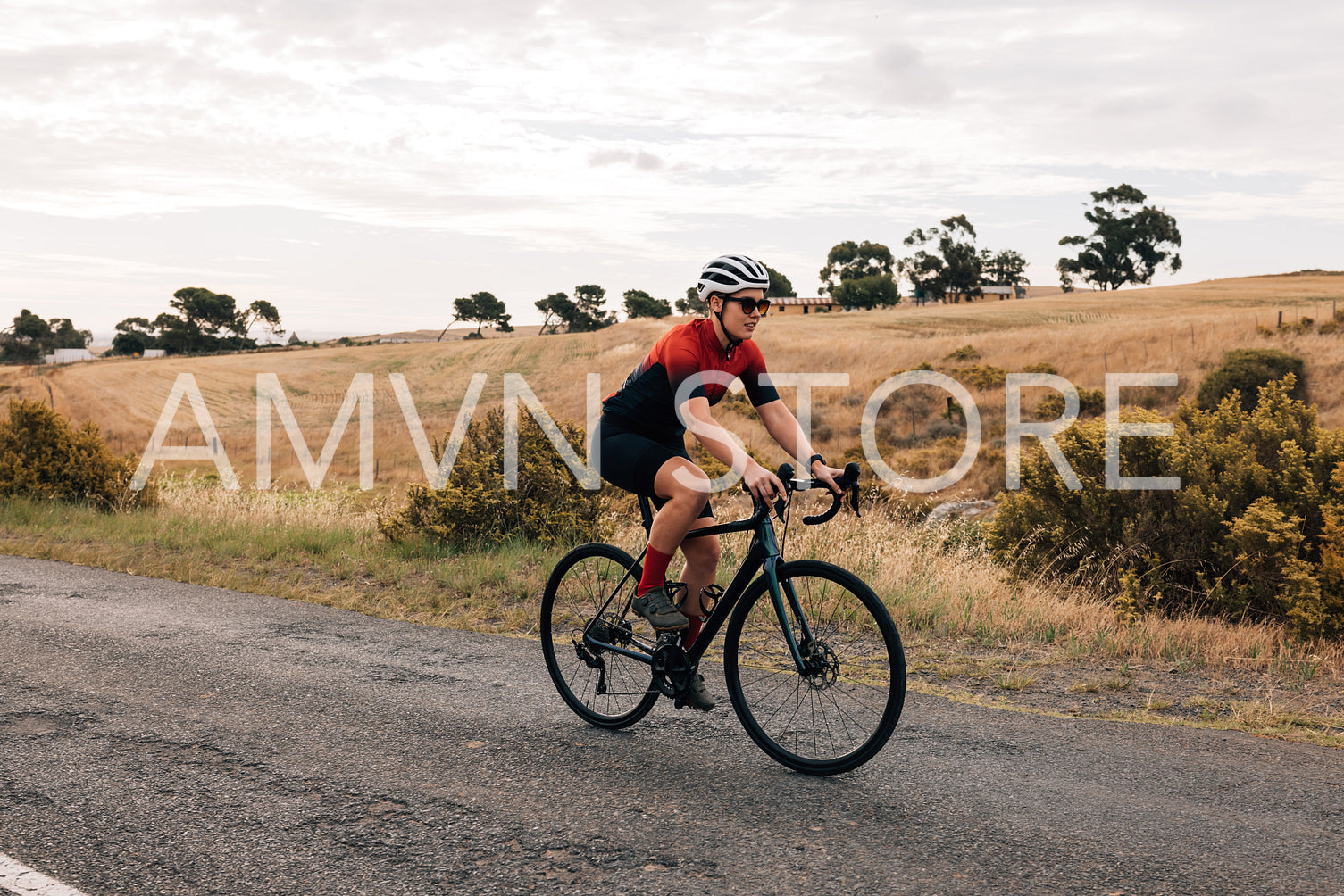 Young healthy cyclist riding a bike on countryside. Professional woman cyclist exercising.