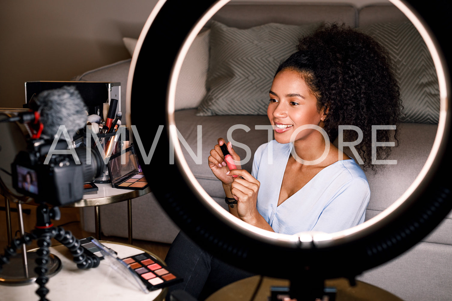 Smiling beauty vlogger recording video for her channel using ring light and digital camera