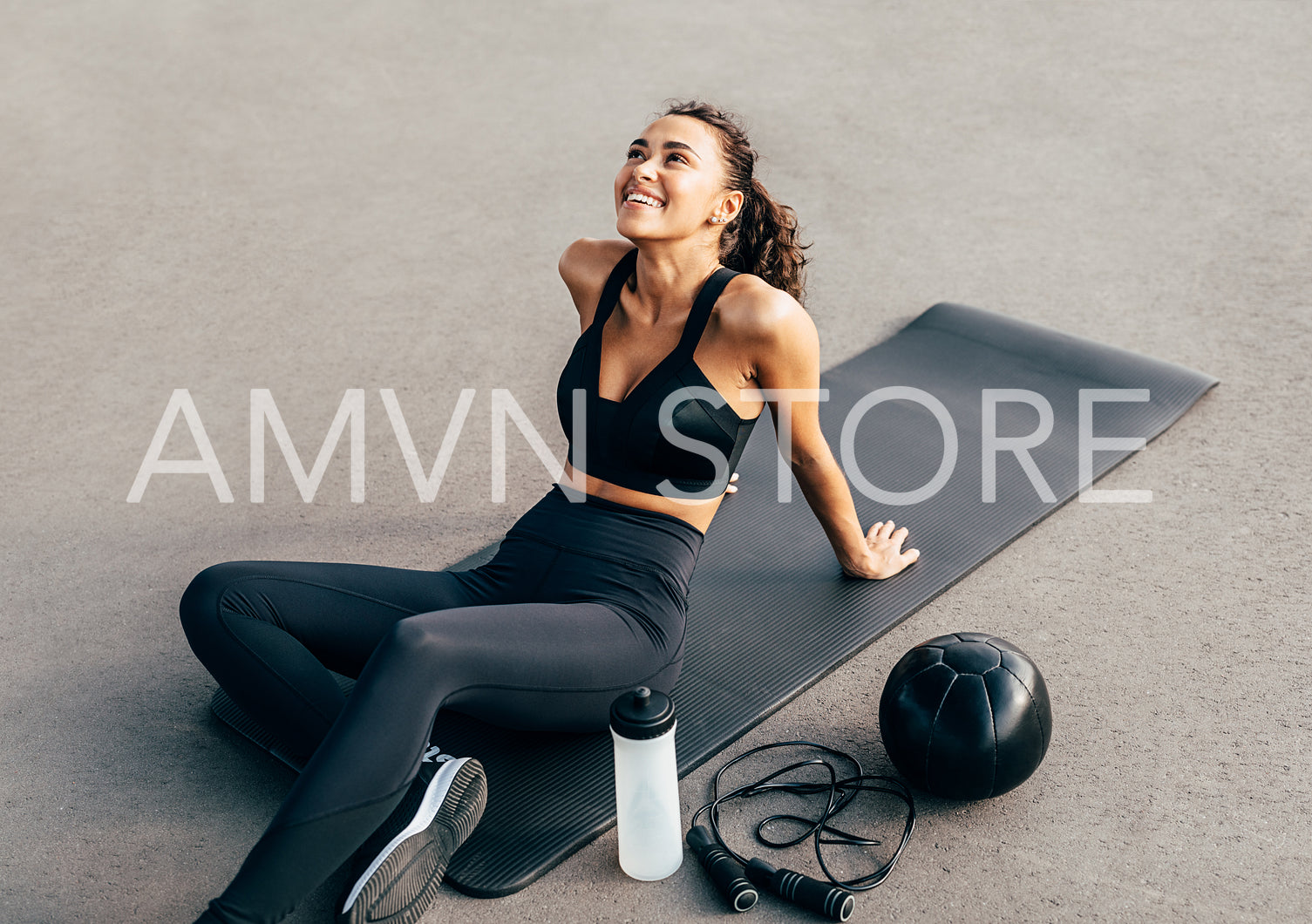 Happy woman sitting on a mat and looking up after evening work out	