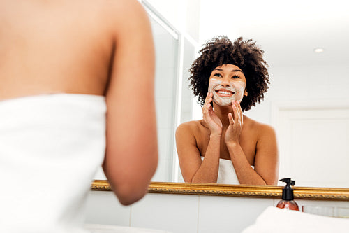 Smiling woman applying natural cream on her face