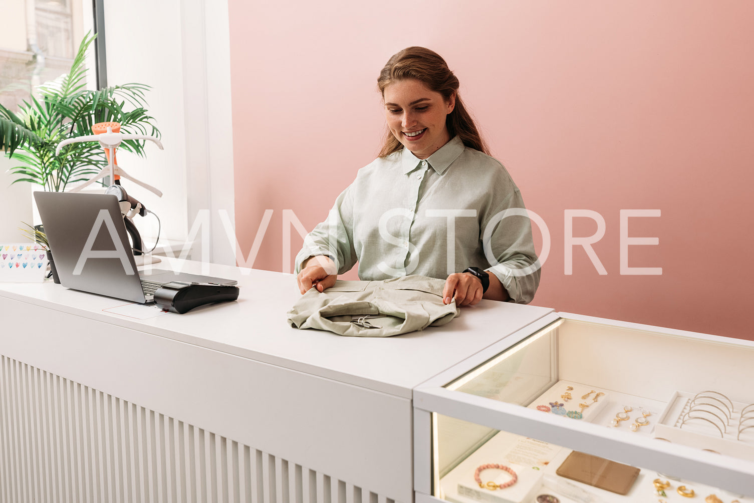 Saleswoman arranging clothes on a counter in store. Clothing sto